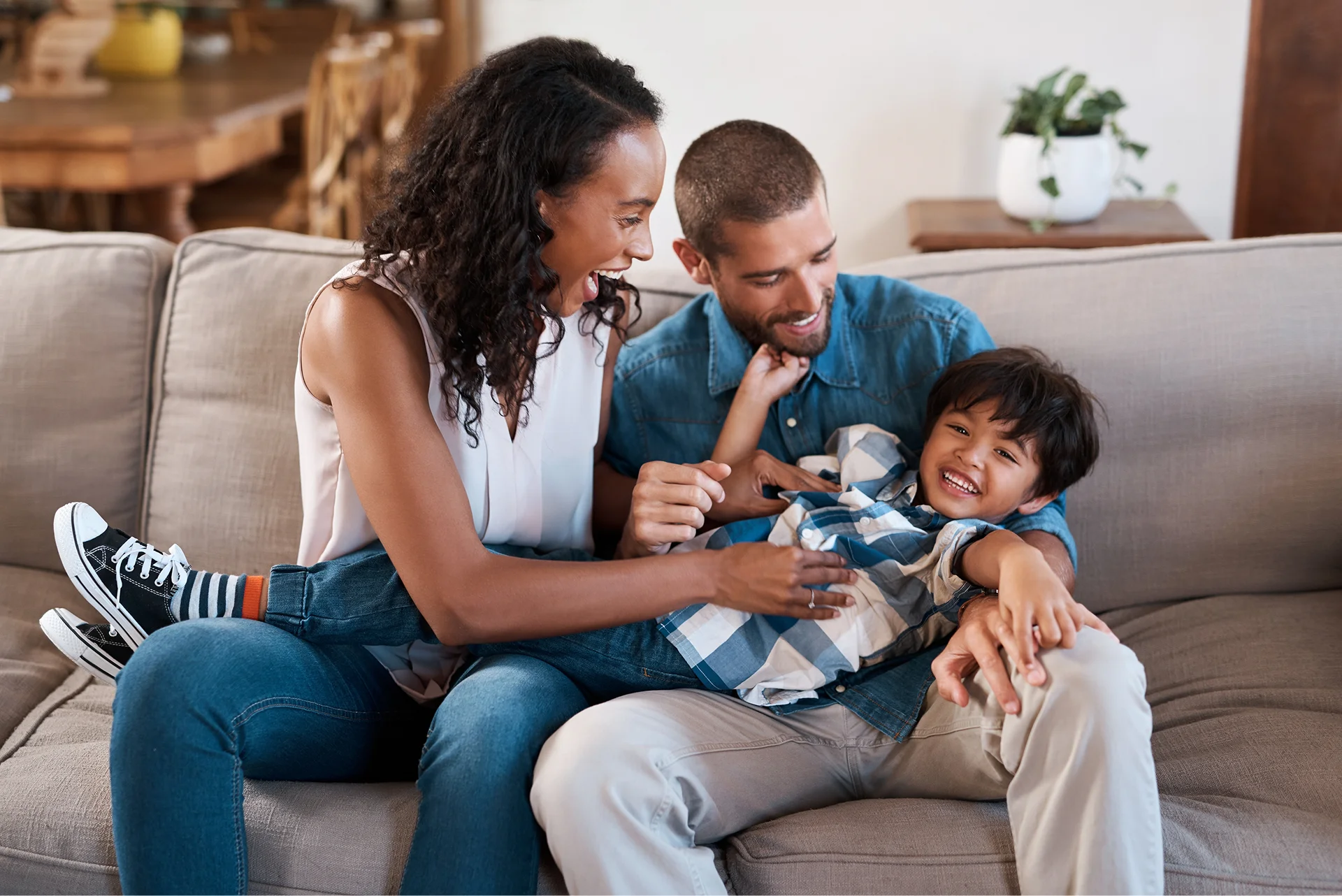Two adults and a child sit on a sofa, smiling in their new Waller TX construction home.