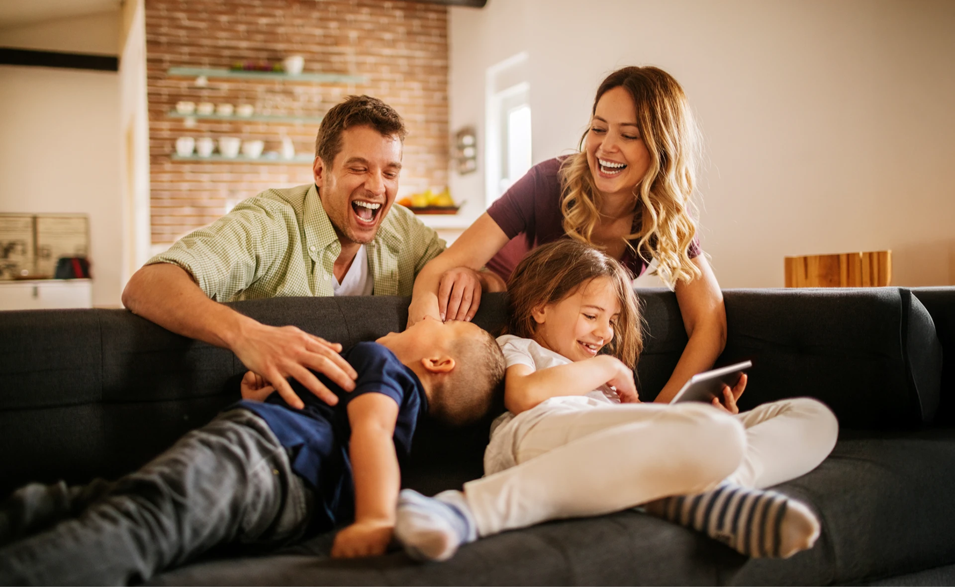 Two adults and two kids laughing and playing together in a Wildrye new home in Waller TX.