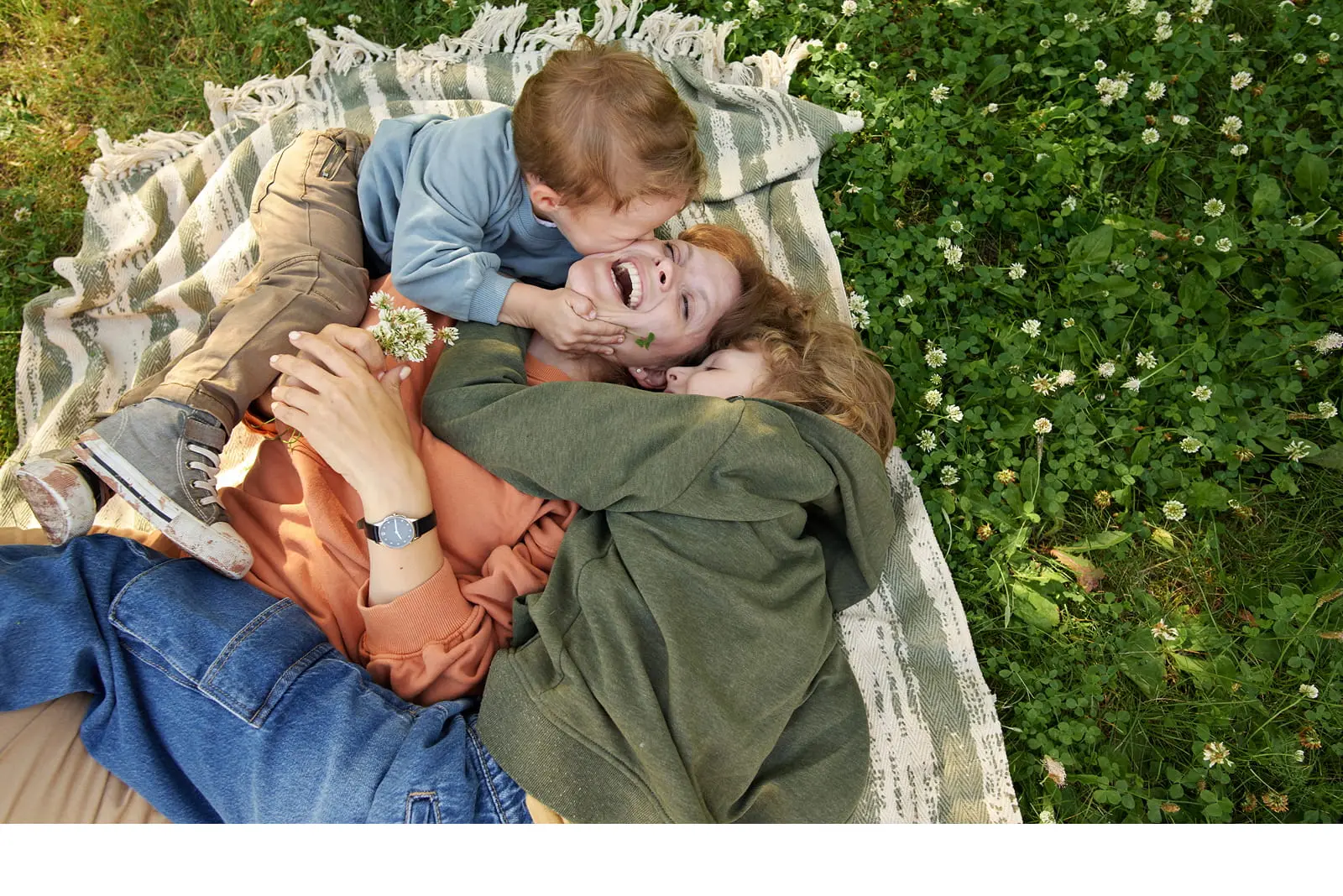 Three people on a blanket in grass, enjoying family time near new homes in Waller TX.